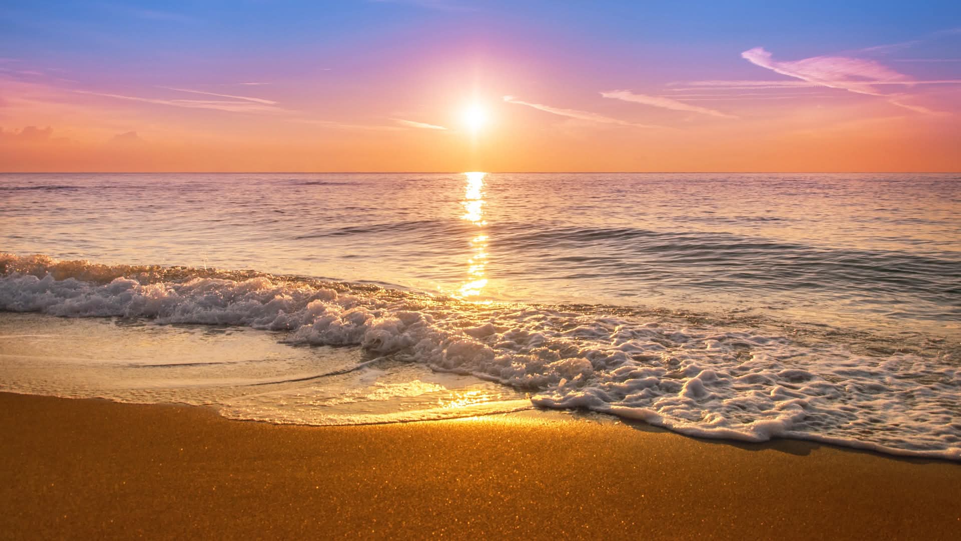 Golden ocean sunset with gentle waves on sandy beach